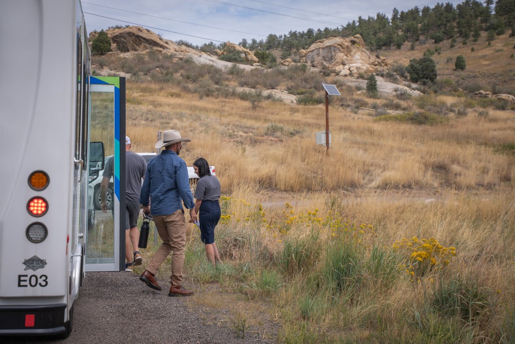 people get off a bus into a grassy area