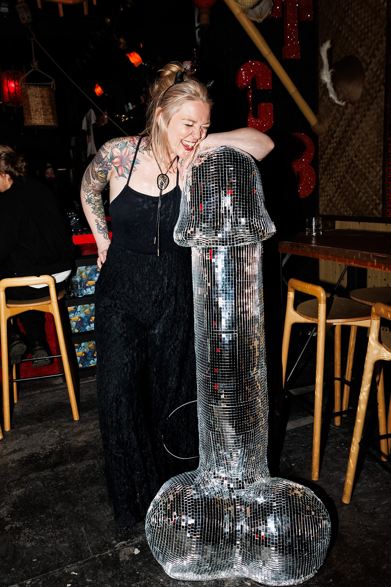 A woman stands next to a giant disco dick