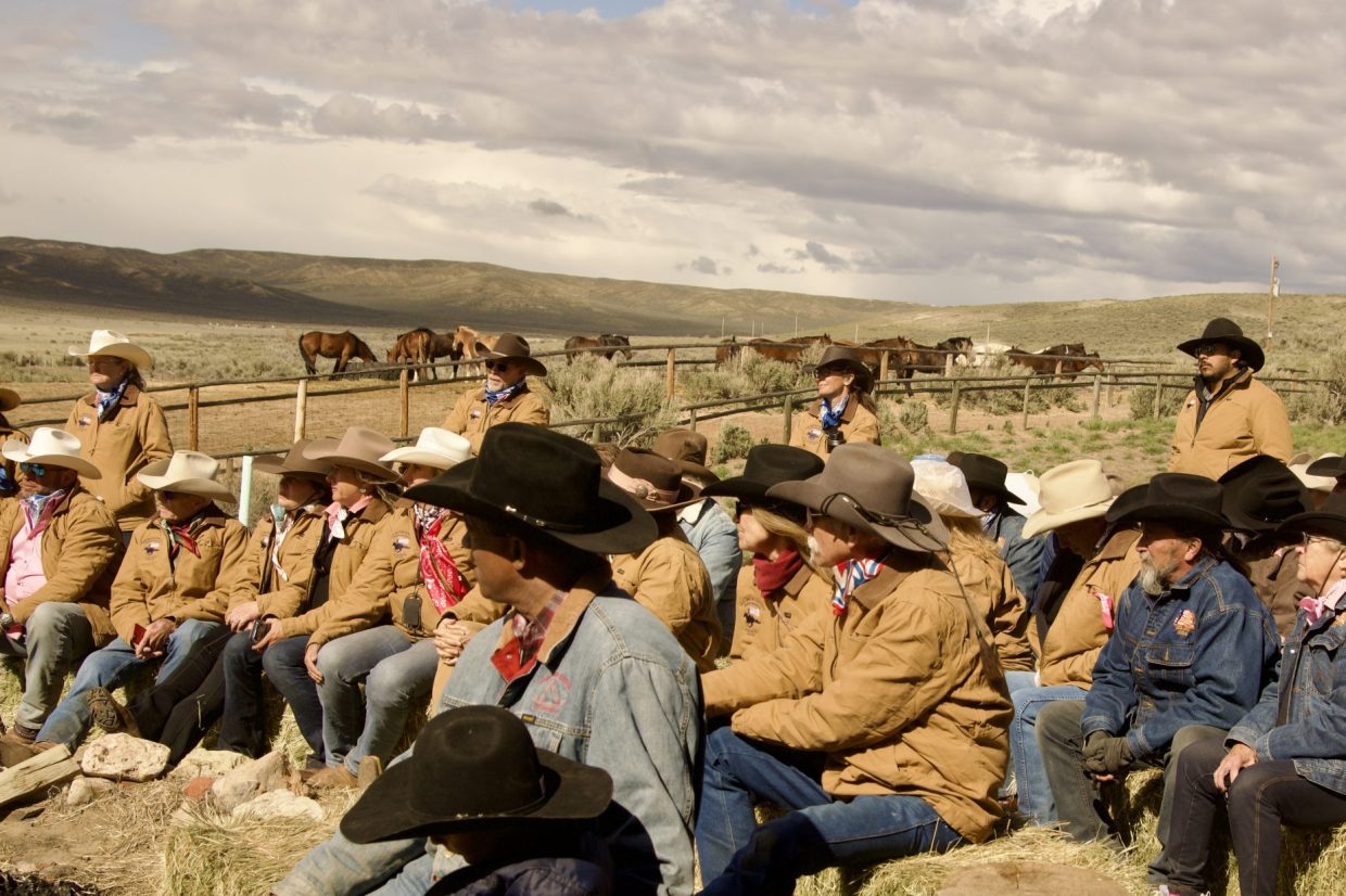 Sombrero Ranch wranglers and guests seated on hay bales, with several horses in the background