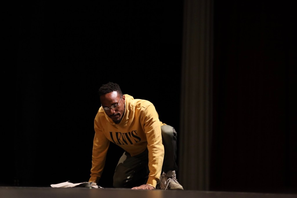 An actor crouches onstage