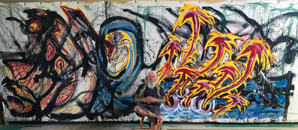 Man sits in front of a colorful canvas