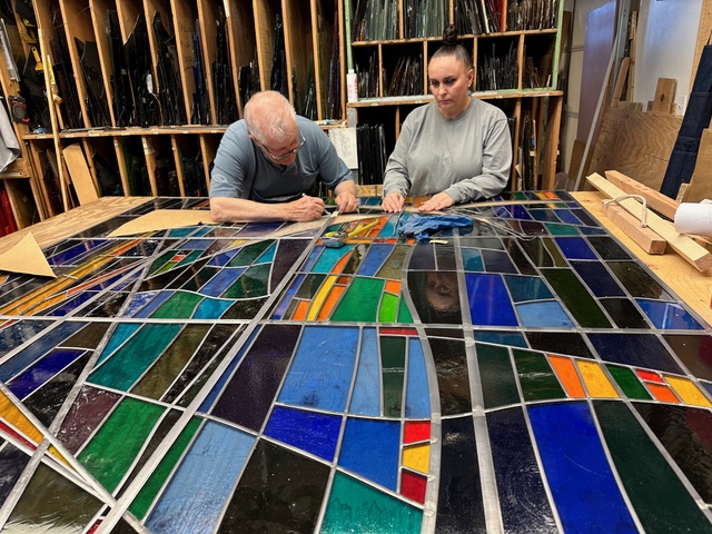 people work on a stained glass window