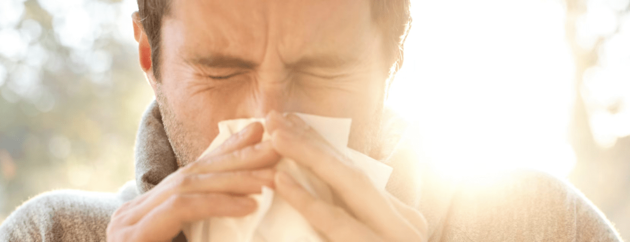 man sneezes into a tissue