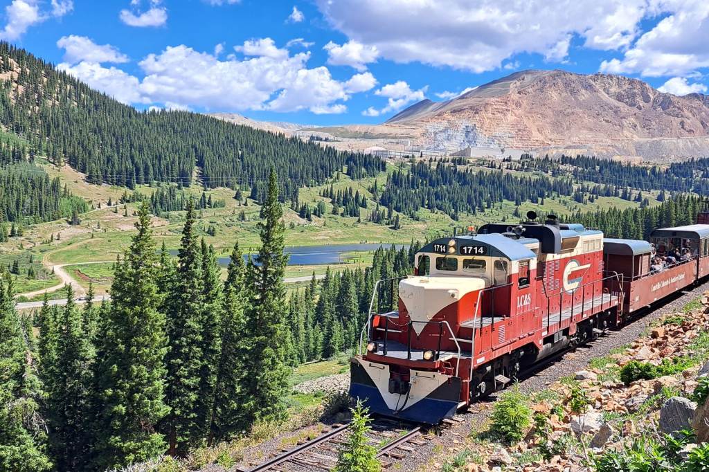 The Leadville Railroad train backdropped by mountains and an evergreen forest