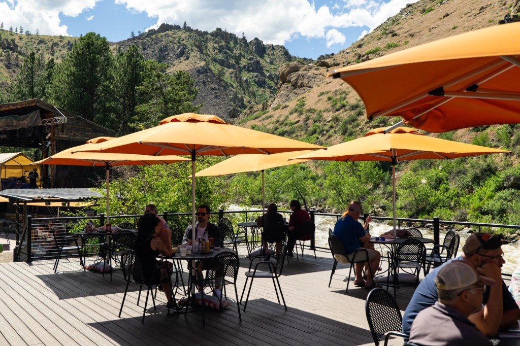 People dining beneath orange umbrellas on the Mishawaka patio