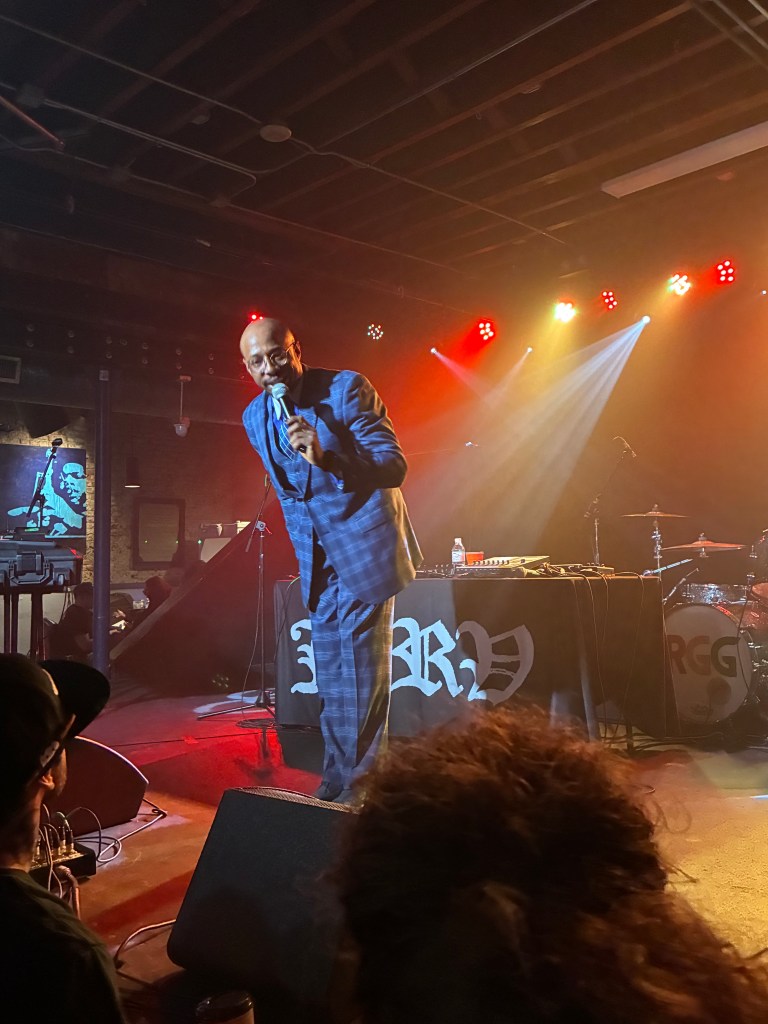 Old Man Saxon in blue plaid suit on stage