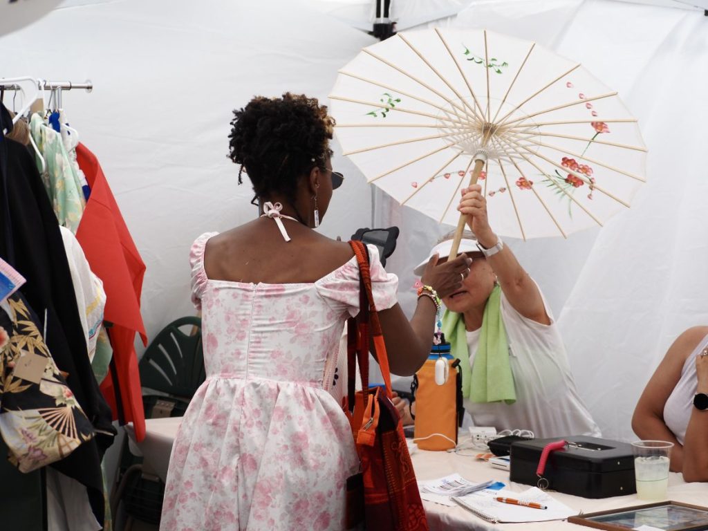 A vendor holds a customer's parasol.