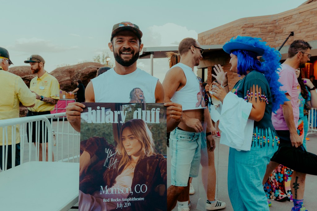 A concertgoer holding a tour poster of Hilary Duff.