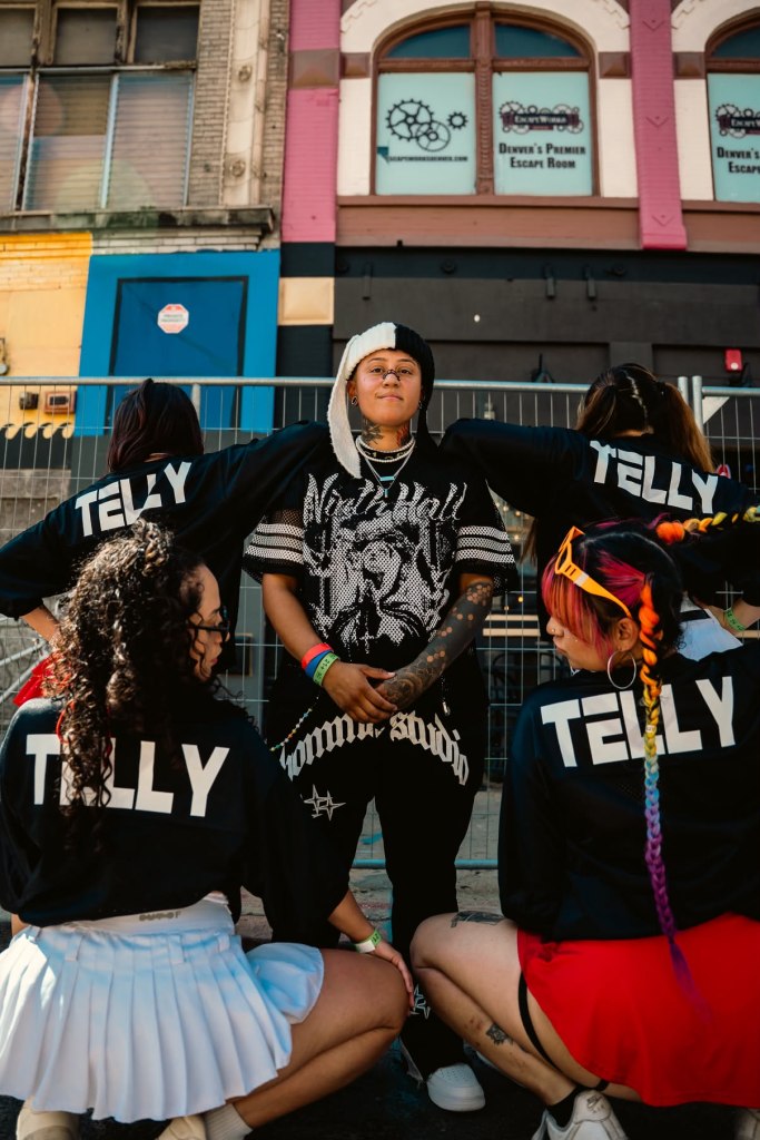 Telly surrounded by dancers wearing shirts with "Telly" on the back