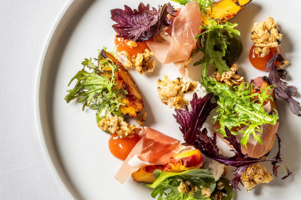 A salad featuring peaches, speck and greens