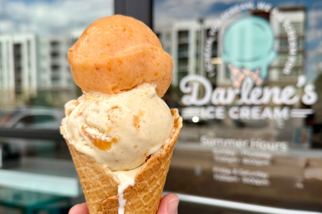 Peach sorbet and peach ice cream stacked on a cone