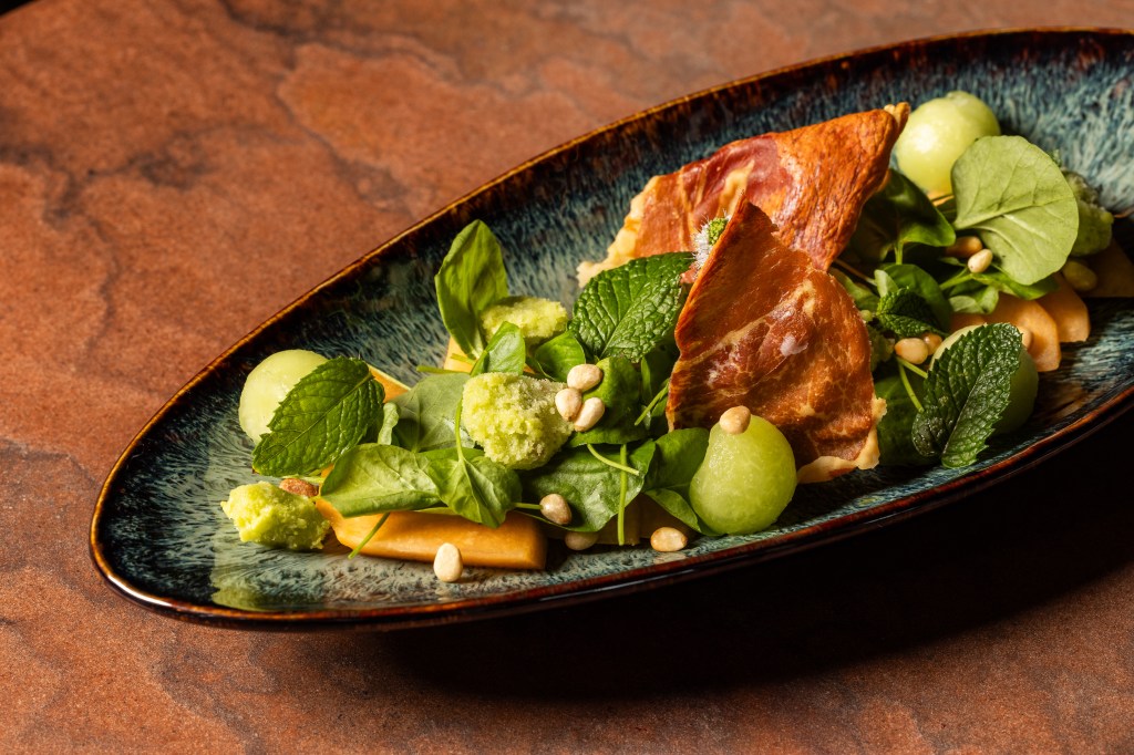 A salad featuring peaches, crispy prosciutto and greens