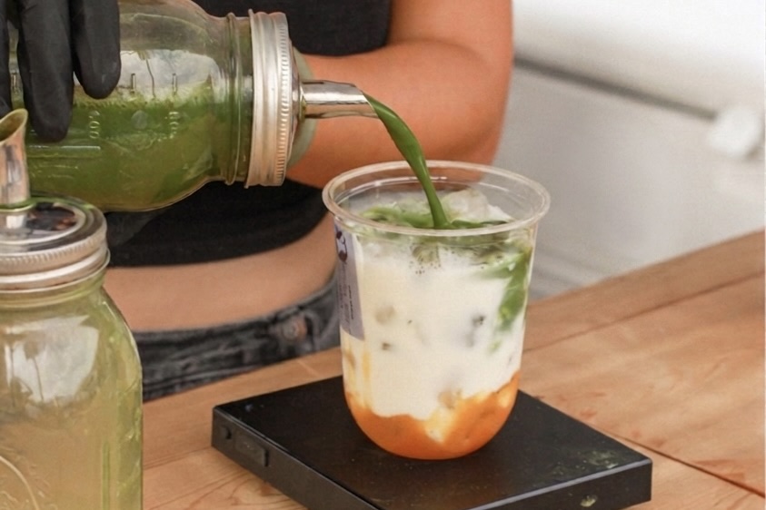 Matcha concentrate being poured into a peach latte