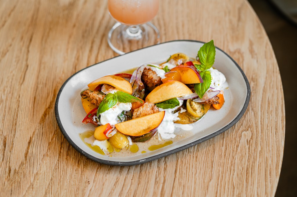 A peach and tomato salad with croutons and stracciatella