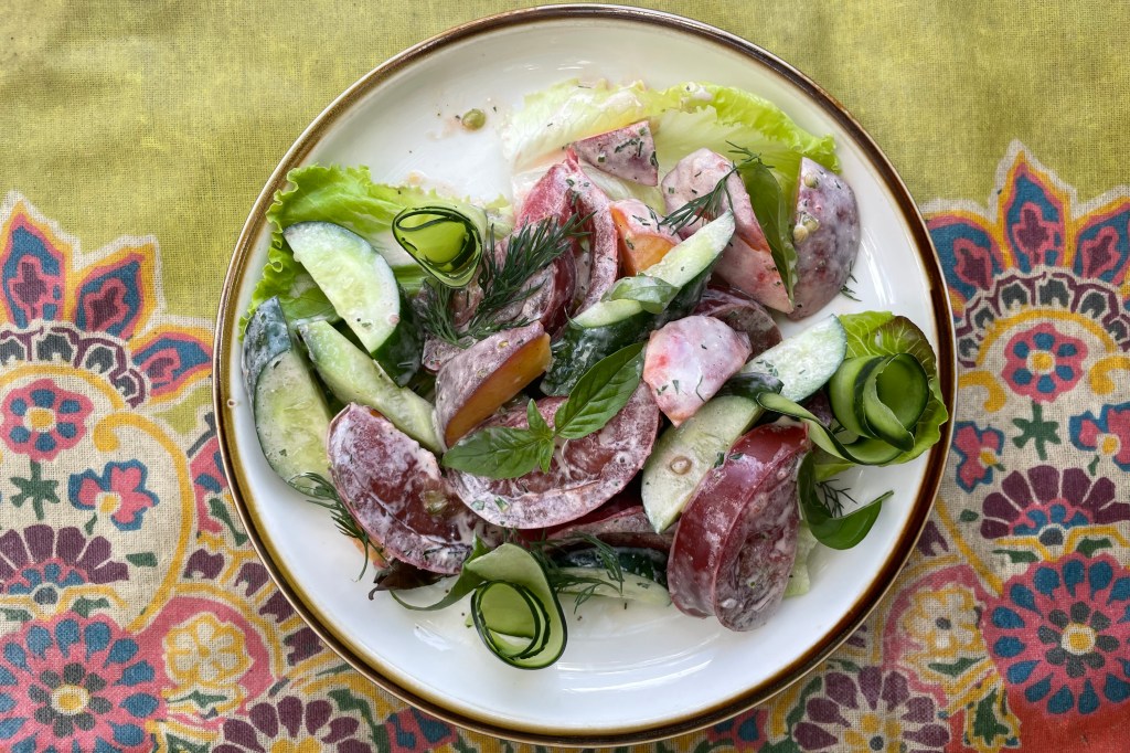 A ranch-dressed salad with peaches, tomatoes and lettuce