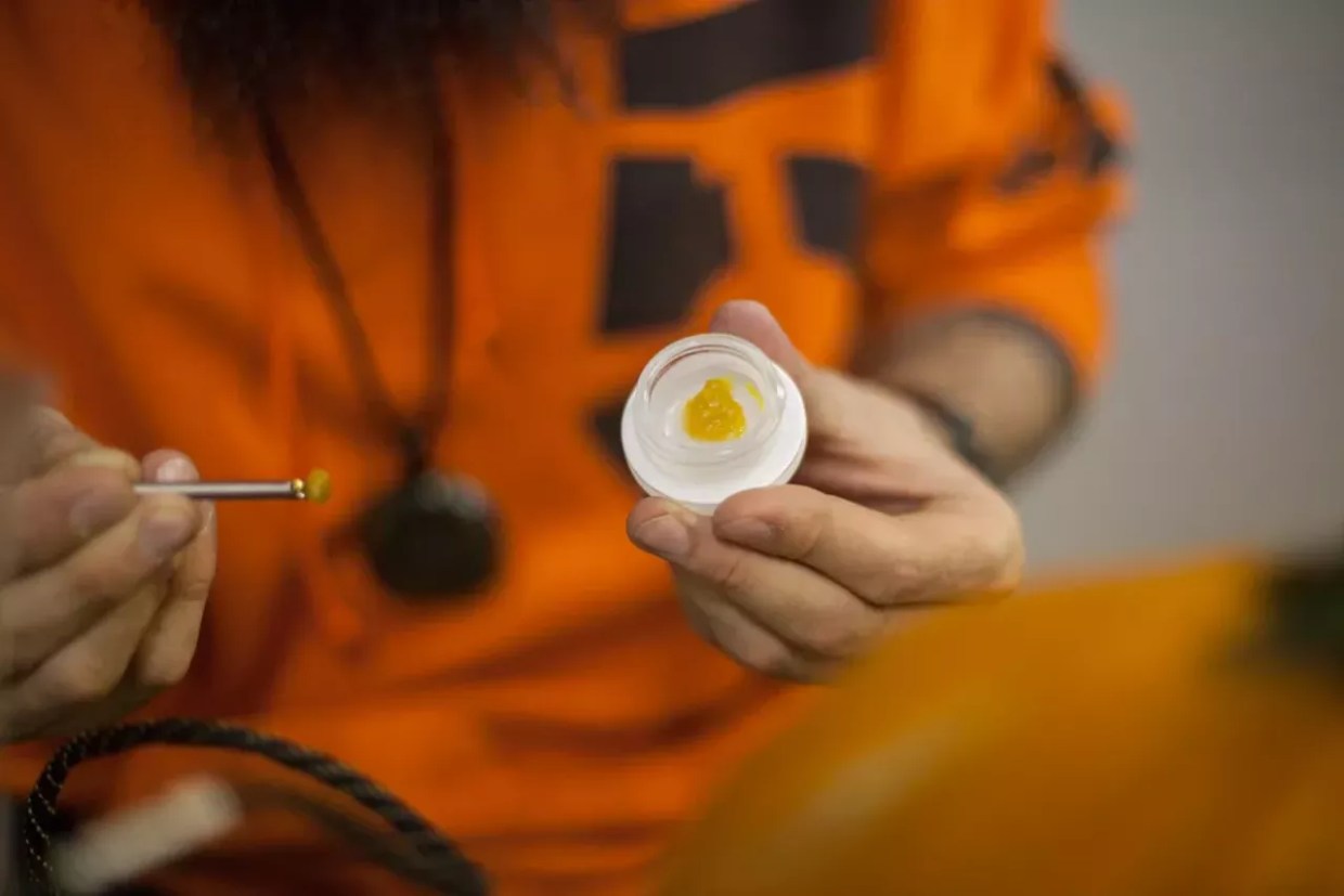 A jar of THC wax as a man loads a dab