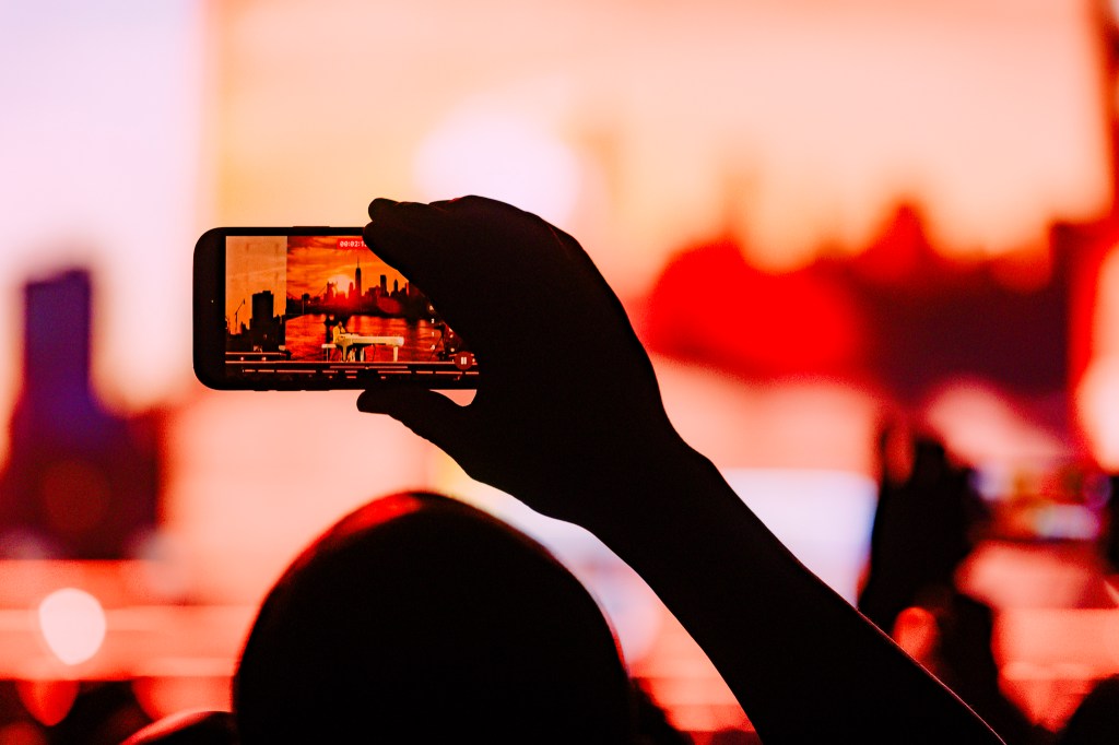 A photo showing Lionel Richie through the perspective of a concertgoer's cellphone.