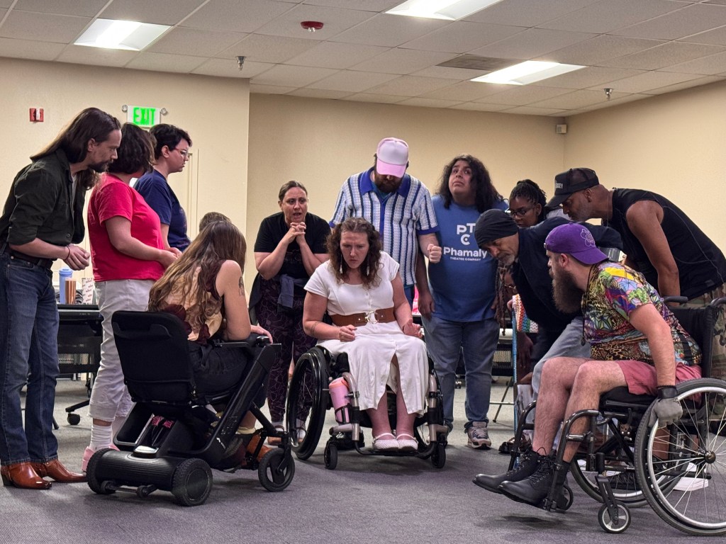 A group of people gather around a woman in a wheelchair