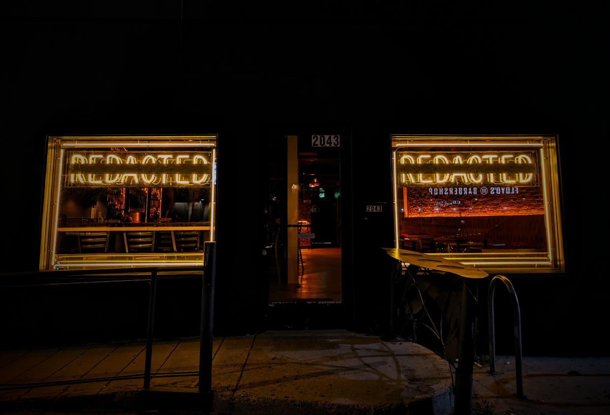 "redacted" neon sign in a window