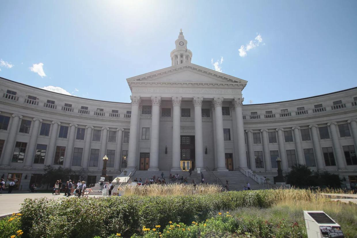 A tall, columned stone building in front of a blue sky.
