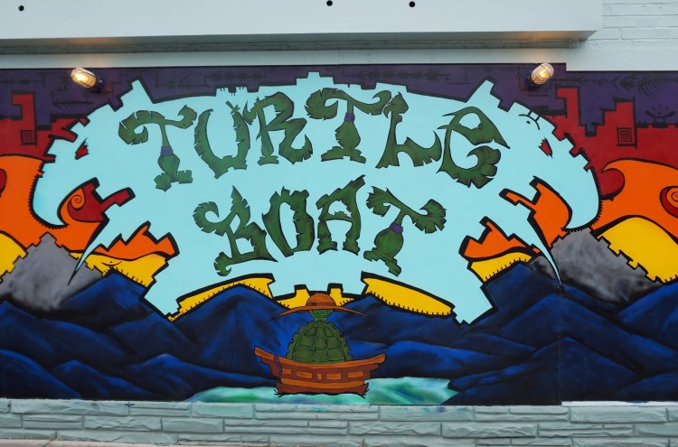 a colorful mural that says "turtle boat"