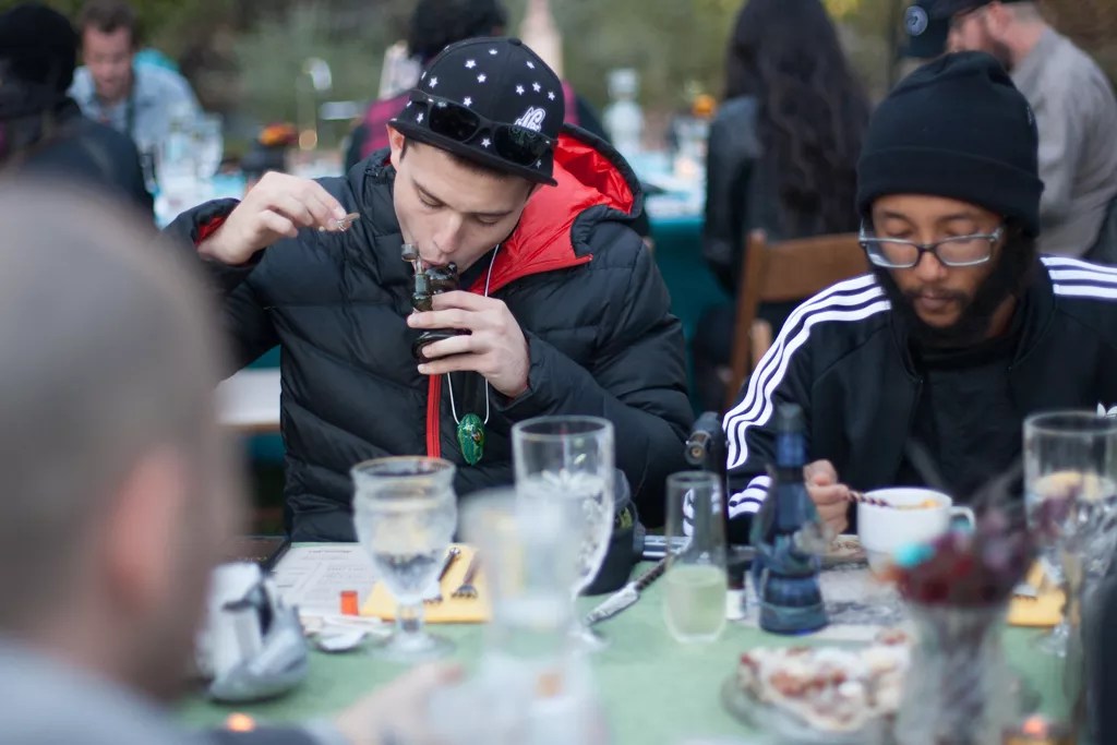 man hits bong at dinner table