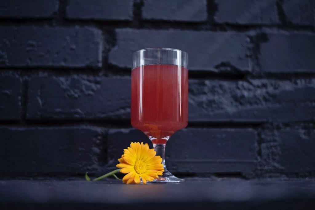 A cocktail with a yellow flower next to it