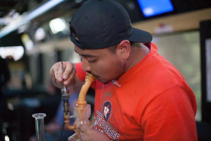 Man in orange shirt hits a bong