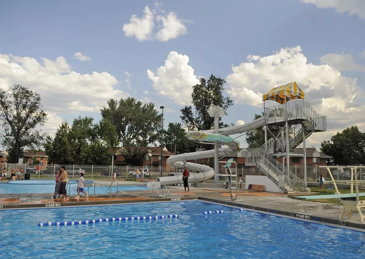 A white water slide winds its way into a blue, rectangular pool.