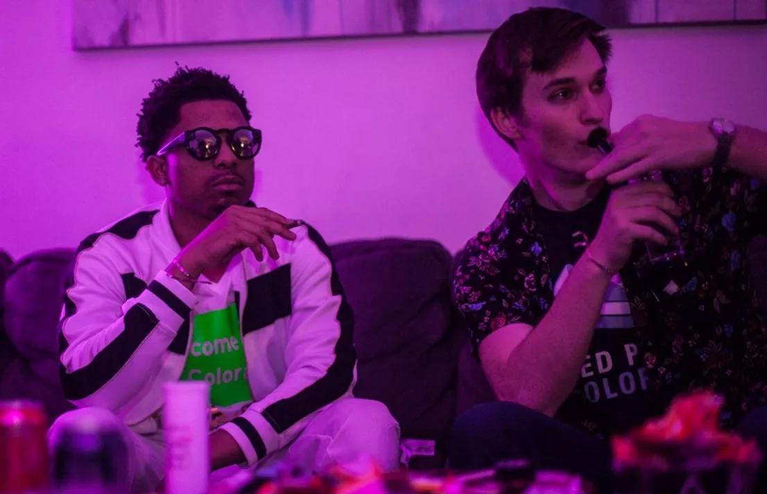 two guys smoke weed on a couch