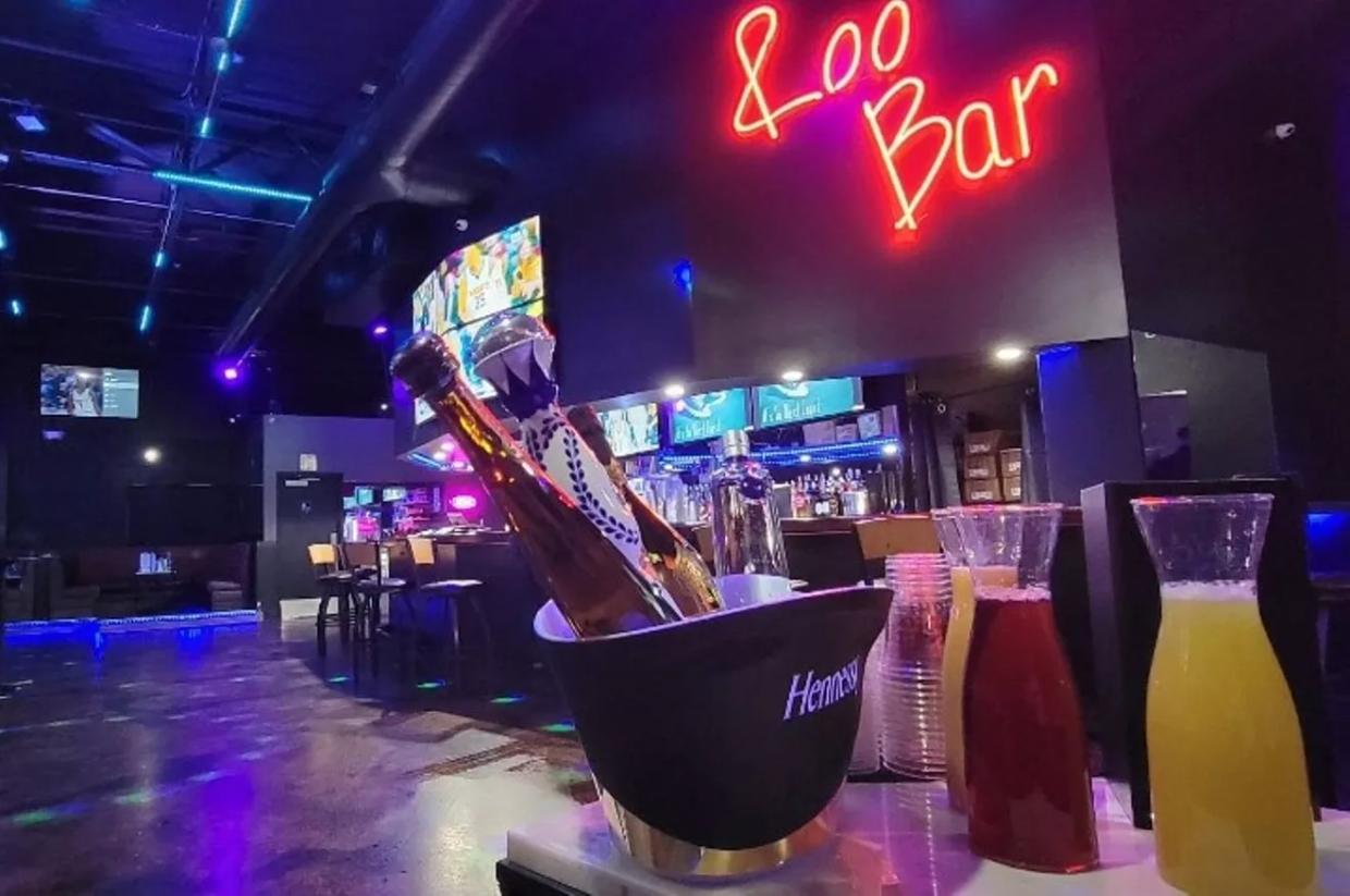 A cocktail sits on a bar top in a darkened room.