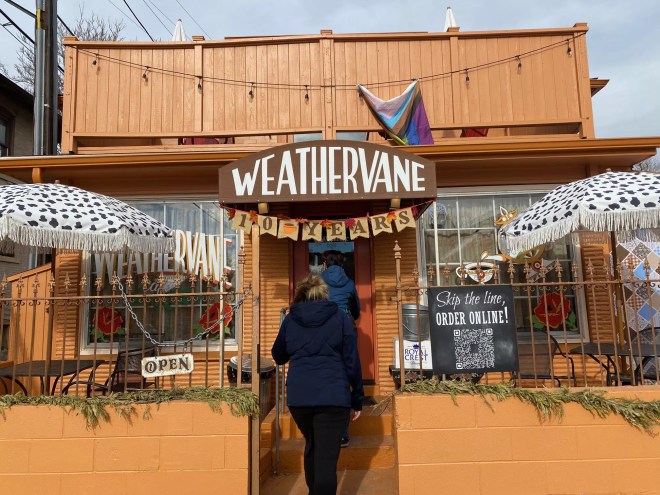 person walking in the front door of a small, tan building
