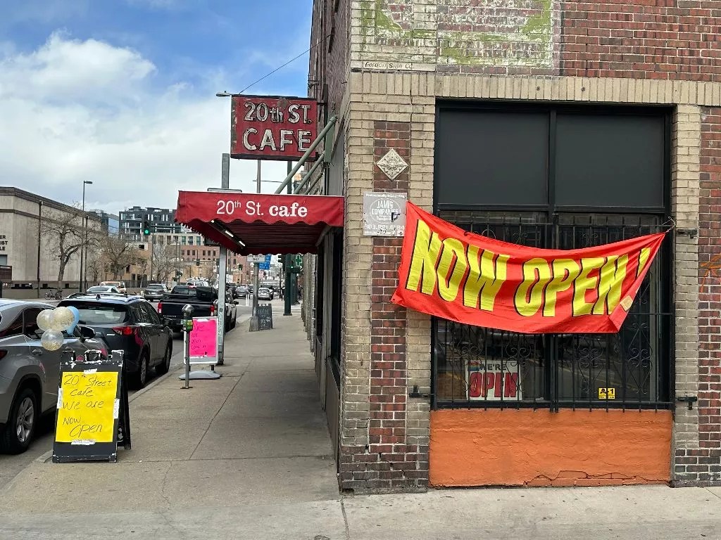 a Now Open sign hangs on a building