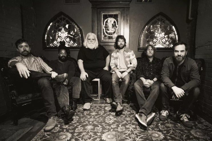 six bandmates sit in a room