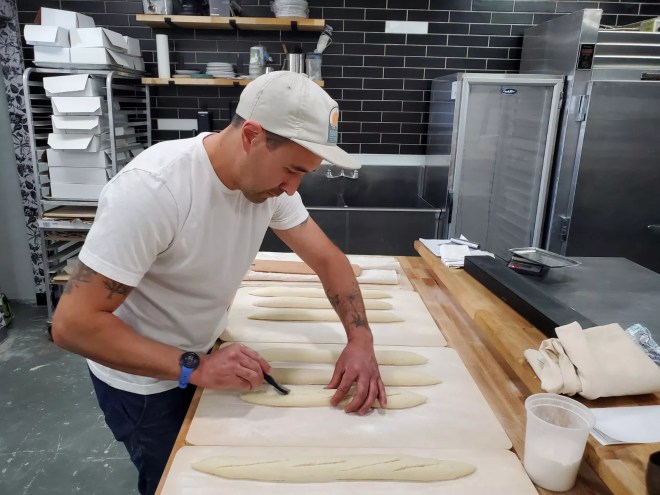 a man scores bread dough in a kitchen