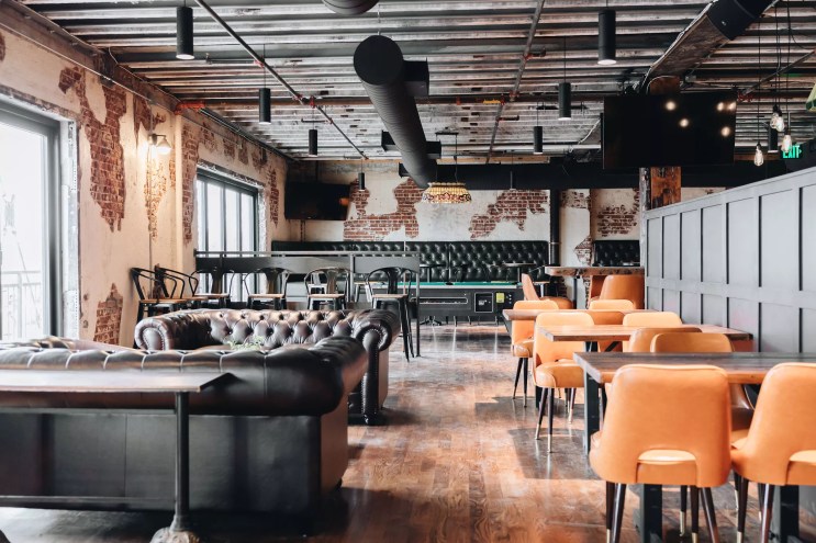 a room with leather couches and tables with orange chairs