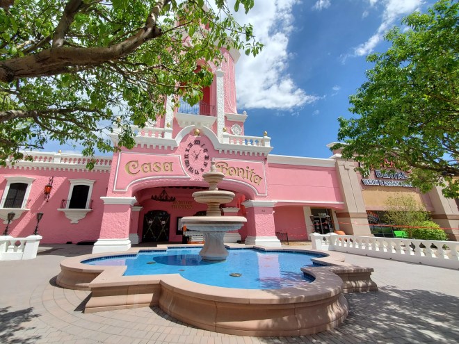 a fountain in front of a pink building