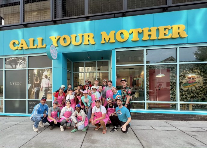 people in pink and blue shirts and aprons posing in front of a blue building