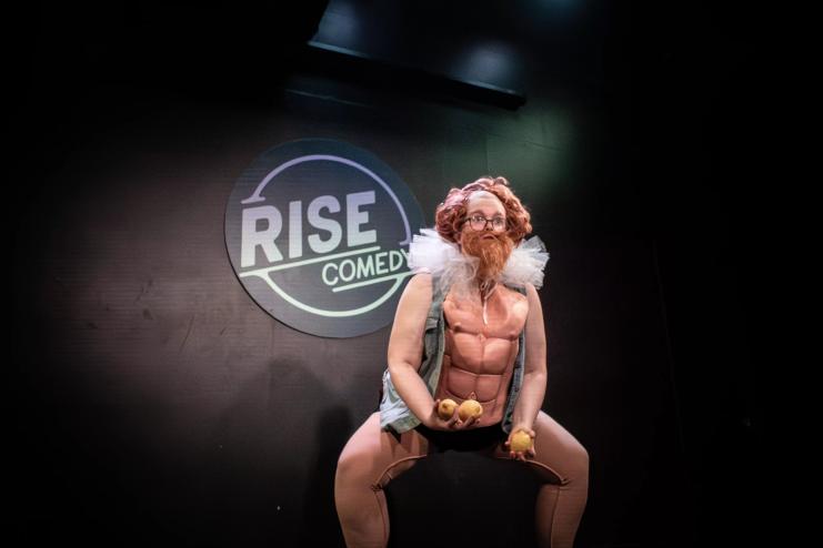 a clown on stage in a bodysuit holding lemons
