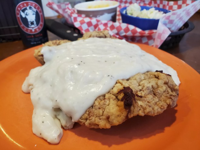 chicken fried steak smothered in white gravy on an orange plate