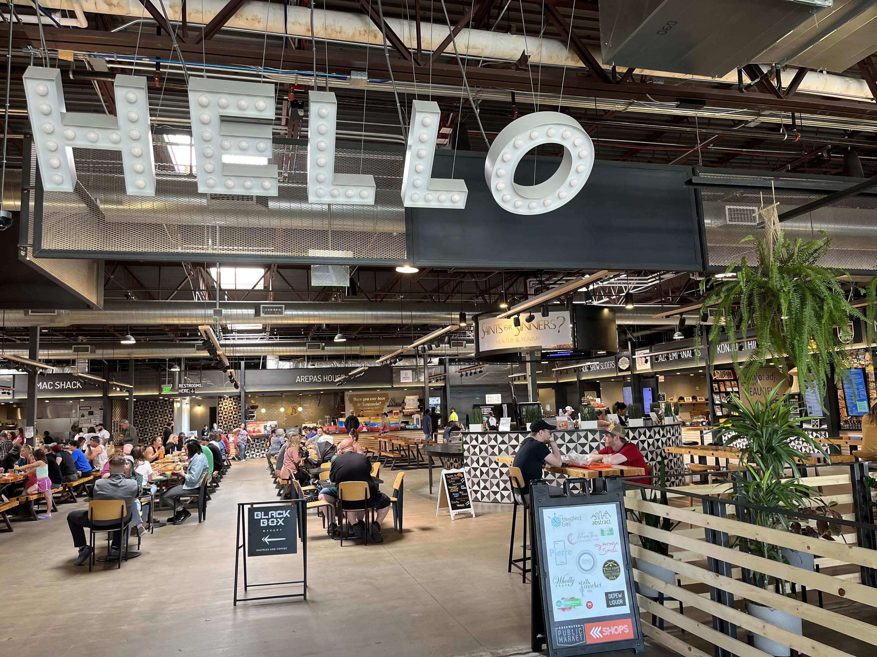 large letters that spell hello hanging from the ceiling of a food hall
