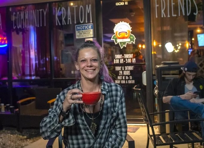 woman outside karma house with cup of kava