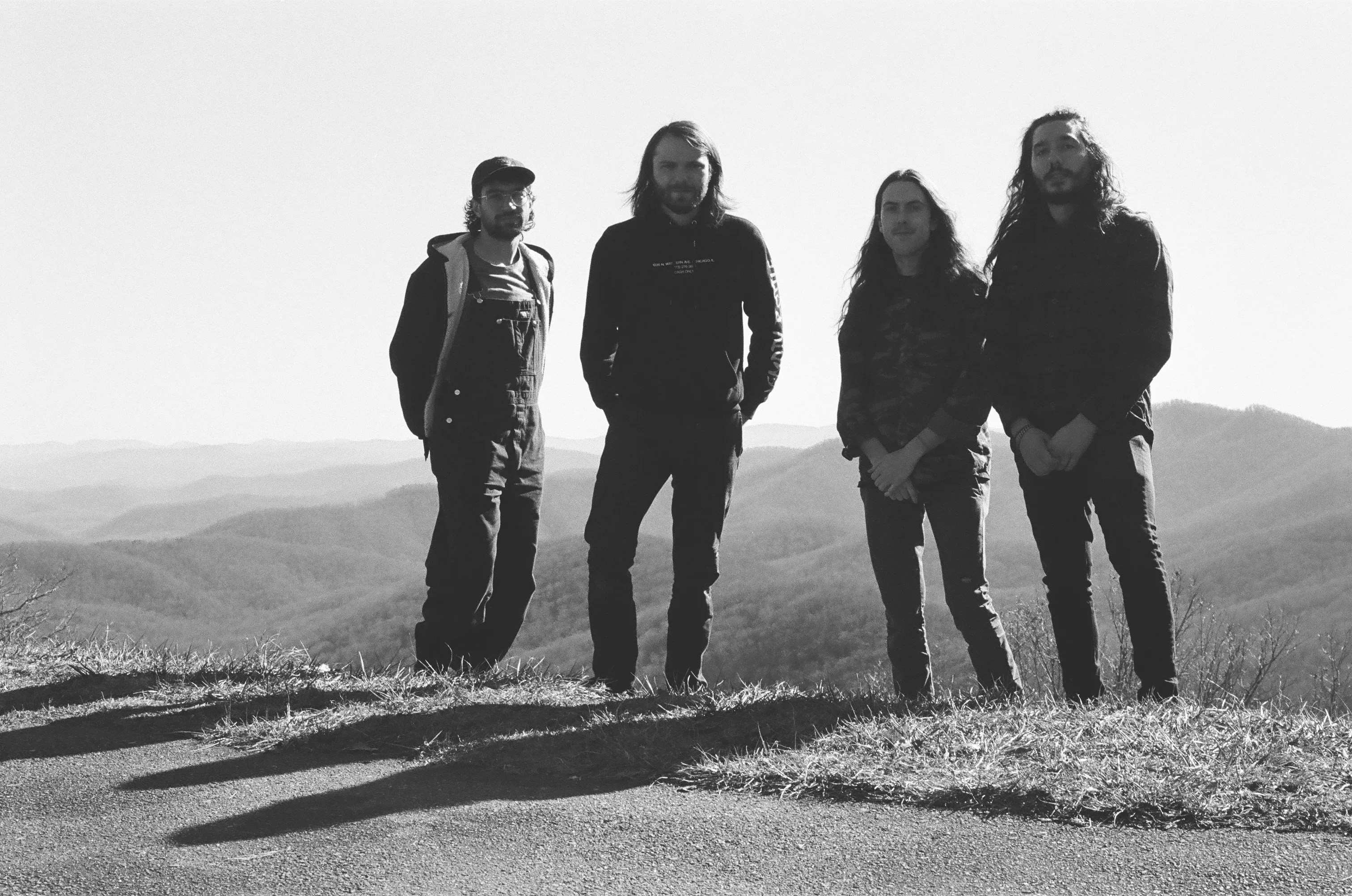 four men with mountains in the background