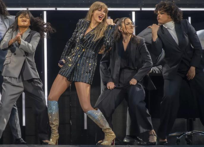 A woman wearing a sparkly suit dances with friends.