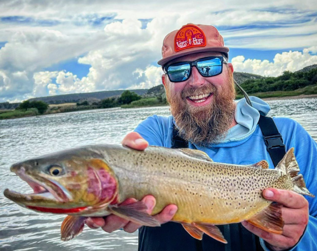 a man in a hat and sunglasses holding a fish