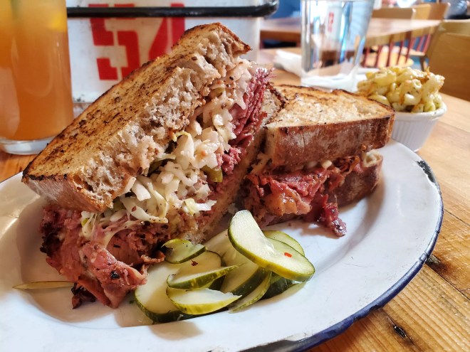 sliced pickles and a pastrami sandwich on a plate