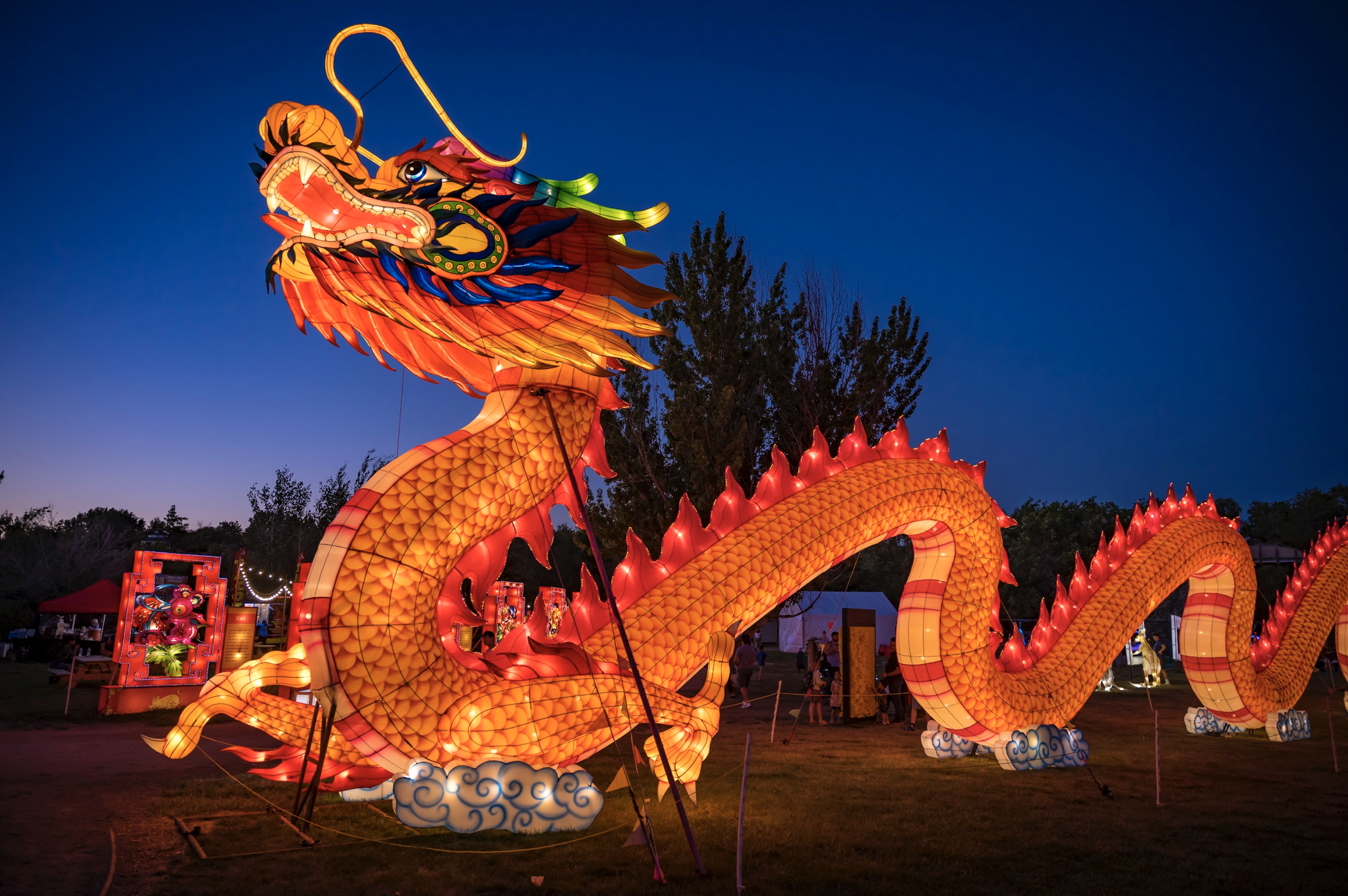 Large glowing dragon lantern made of orange paper against a dark blue sky.