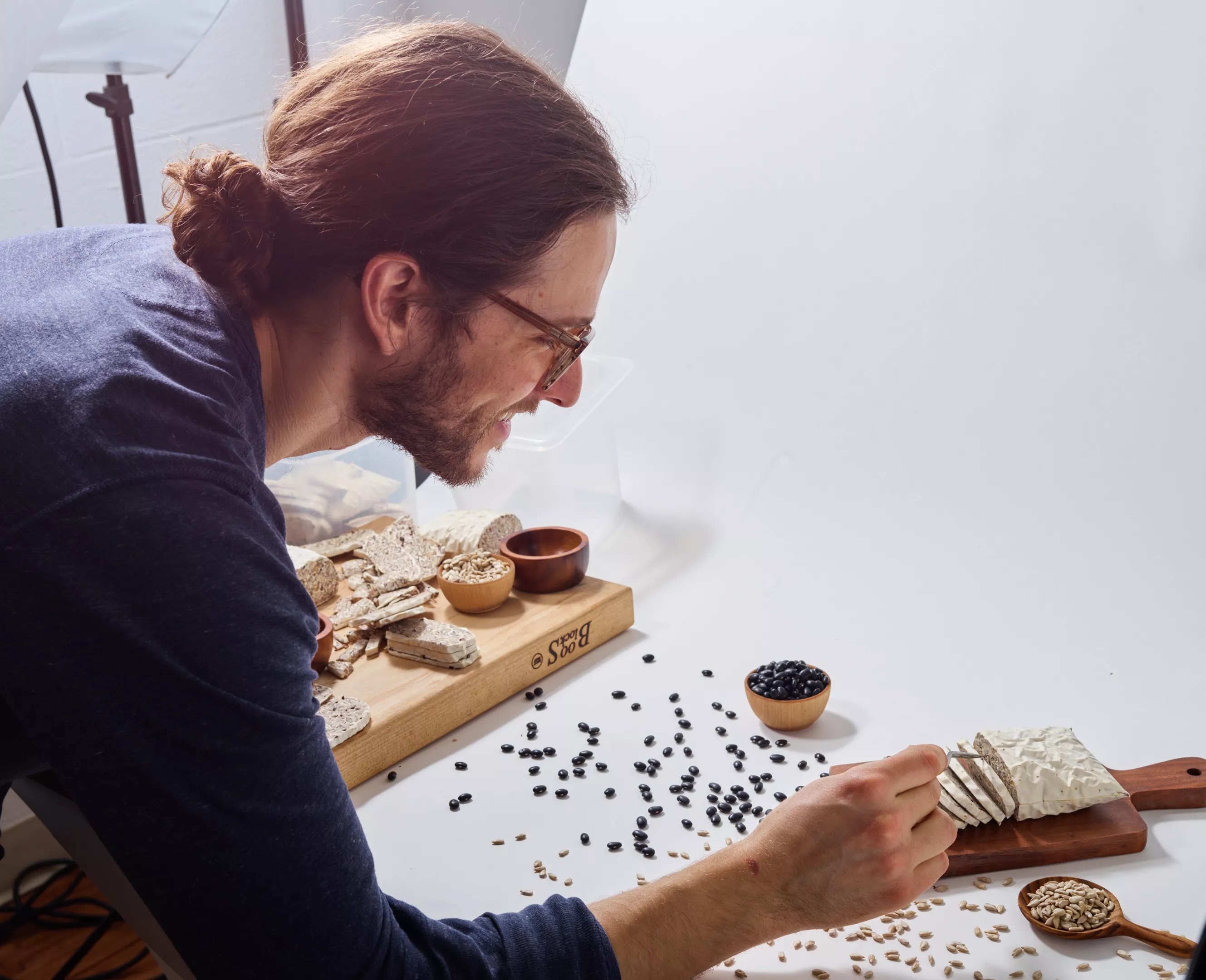 a man holding tweezers leaning over a cutting board