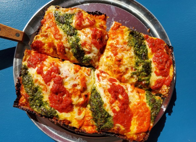 a pizza with strips of marinara, vodka sauce and pesto