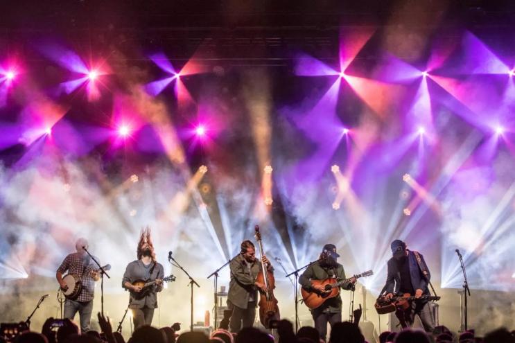 musicians on a stage with purple and white lights